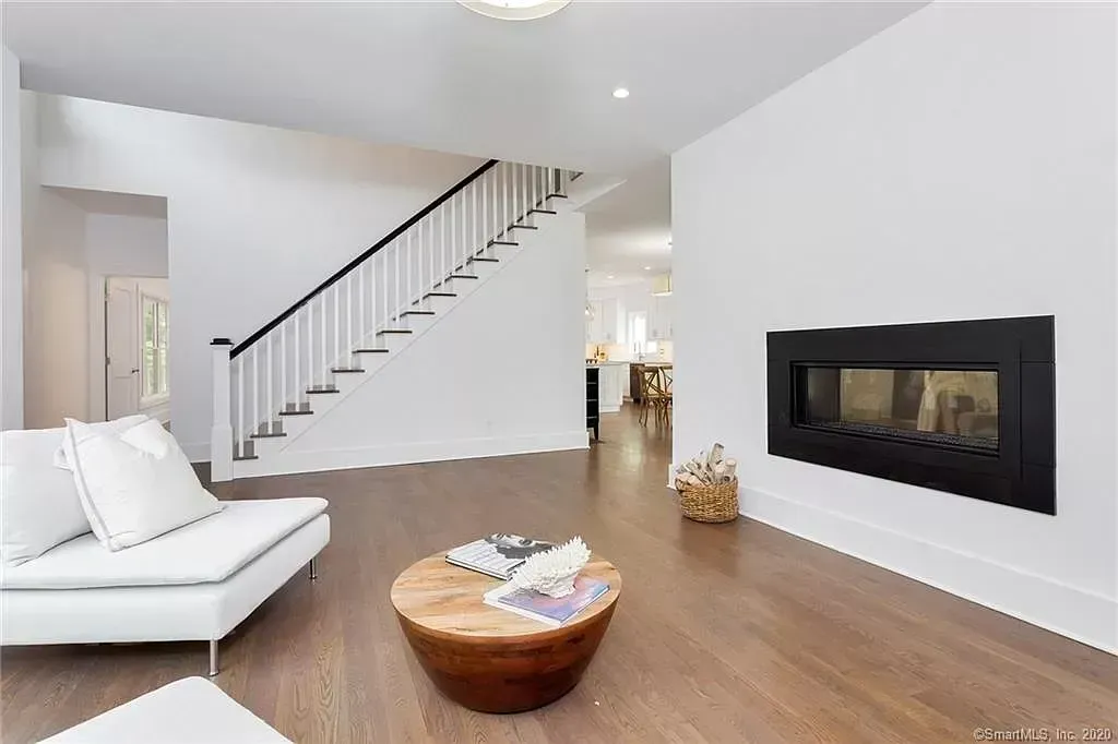 A living room with a couch , coffee table , fireplace and stairs.