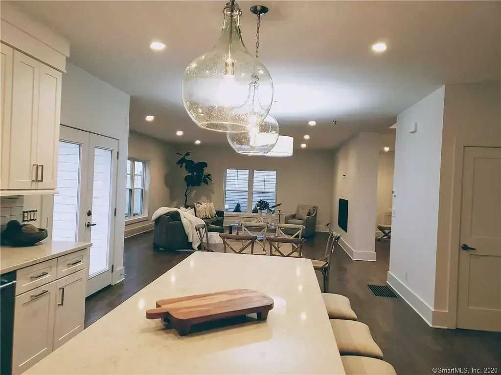 A kitchen with white cabinets and a wooden cutting board on the counter.