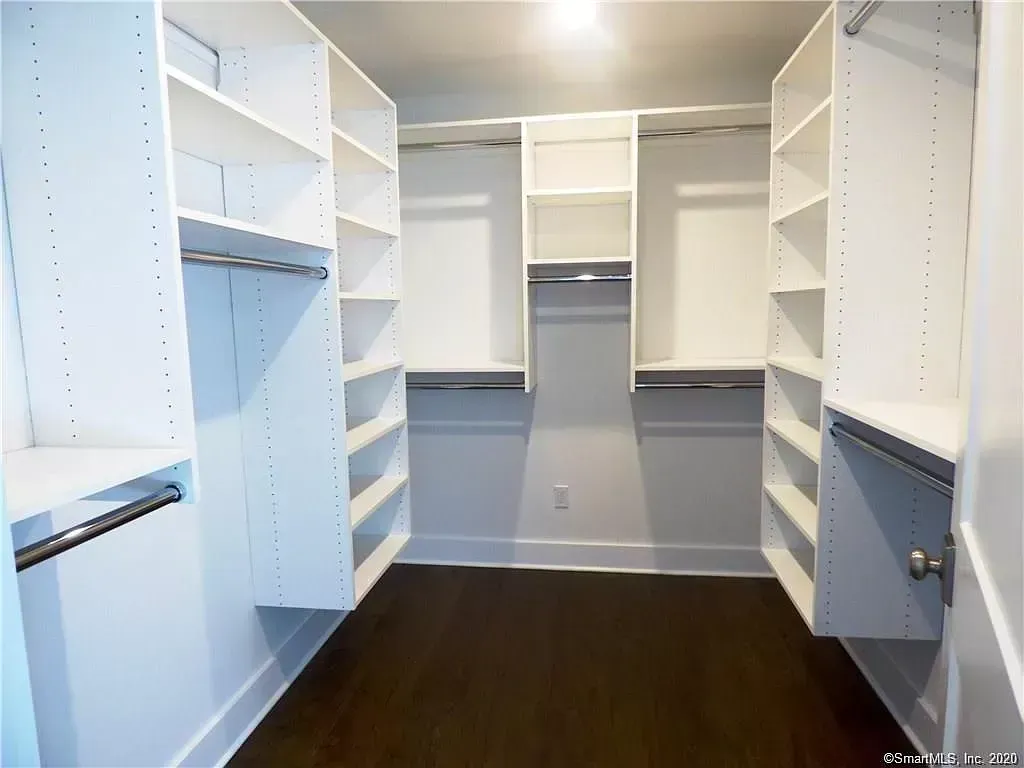 A walk in closet with lots of shelves and clothes racks