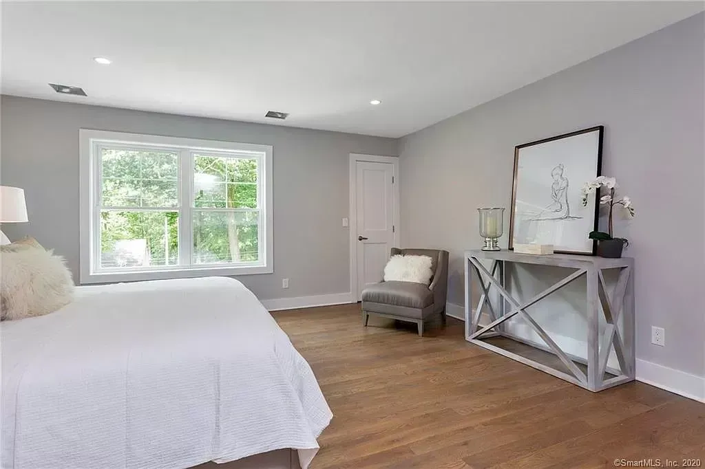 A bedroom with a bed , chair , table and window.
