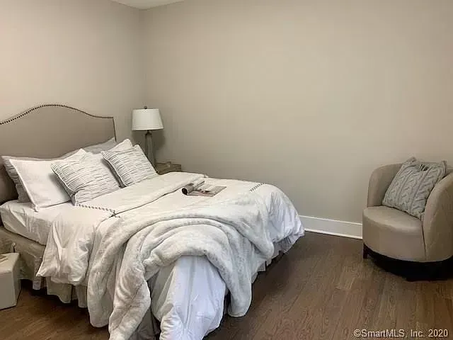 A bedroom with a bed , chair and lamp.