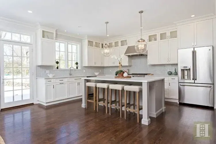A kitchen with white cabinets , stainless steel appliances , and a large island.