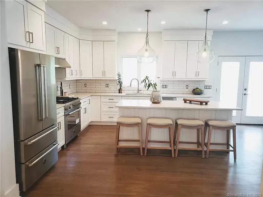 A kitchen with white cabinets , stainless steel appliances , and a large island.