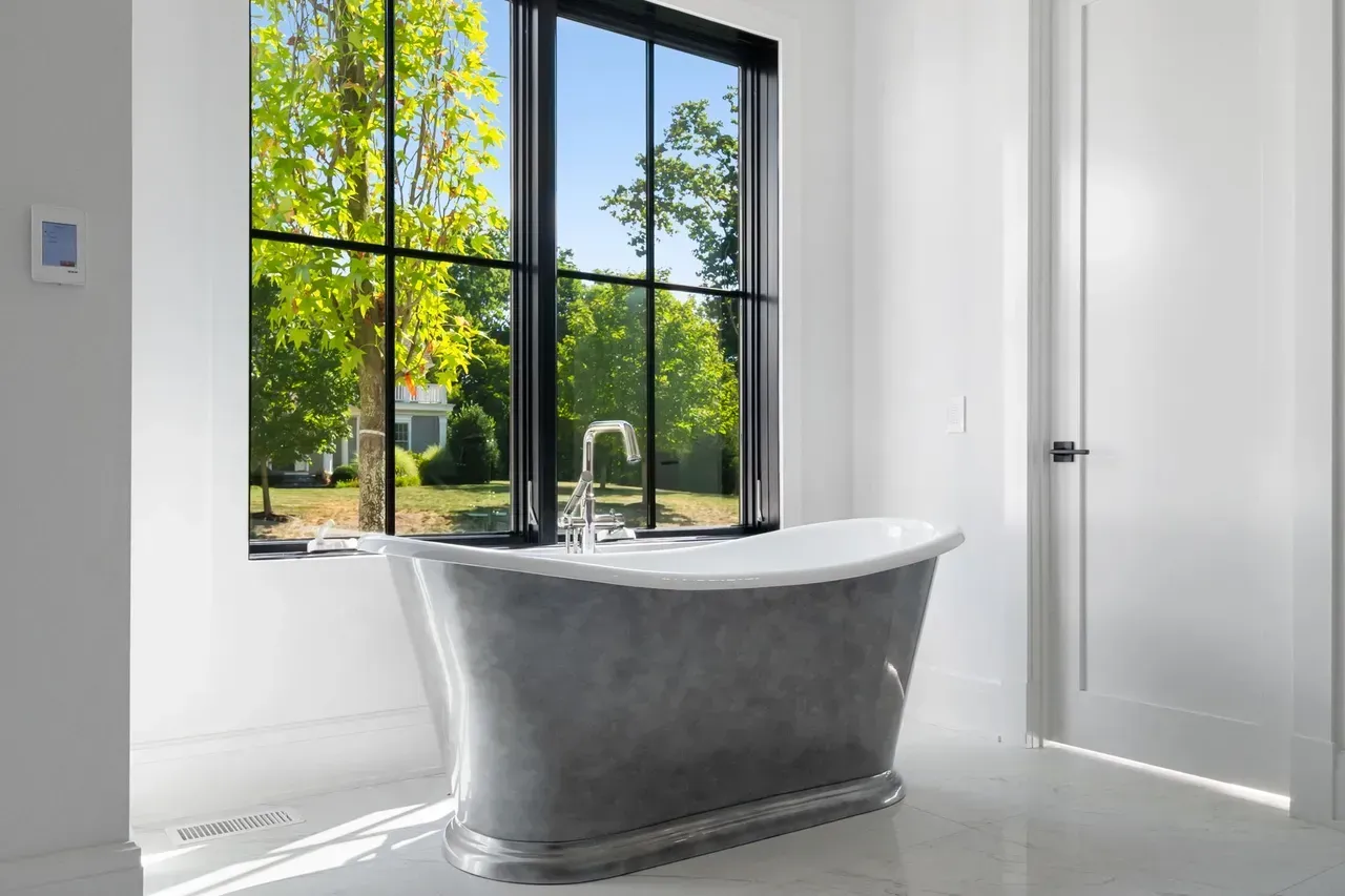 A bathroom with a bathtub and a large window.