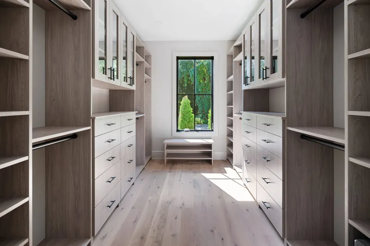 A walk in closet with lots of shelves and drawers