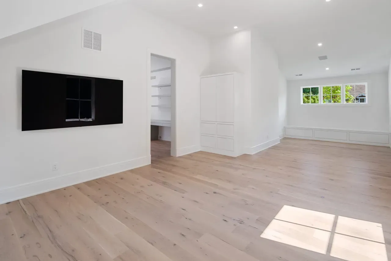 An empty room with hardwood floors and a flat screen tv on the wall.