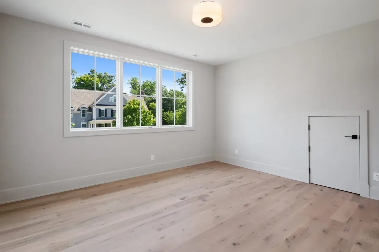 An empty room with hardwood floors and three windows.