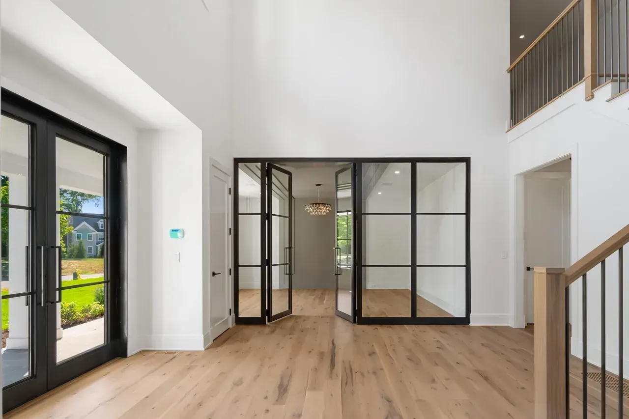 A large empty room with hardwood floors and a staircase.