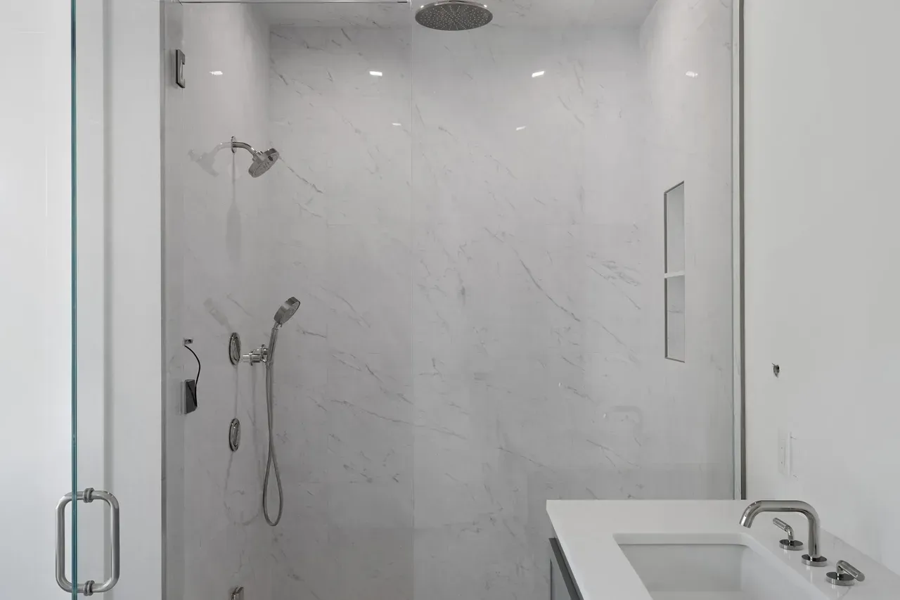 A bathroom with a walk in shower and a sink.