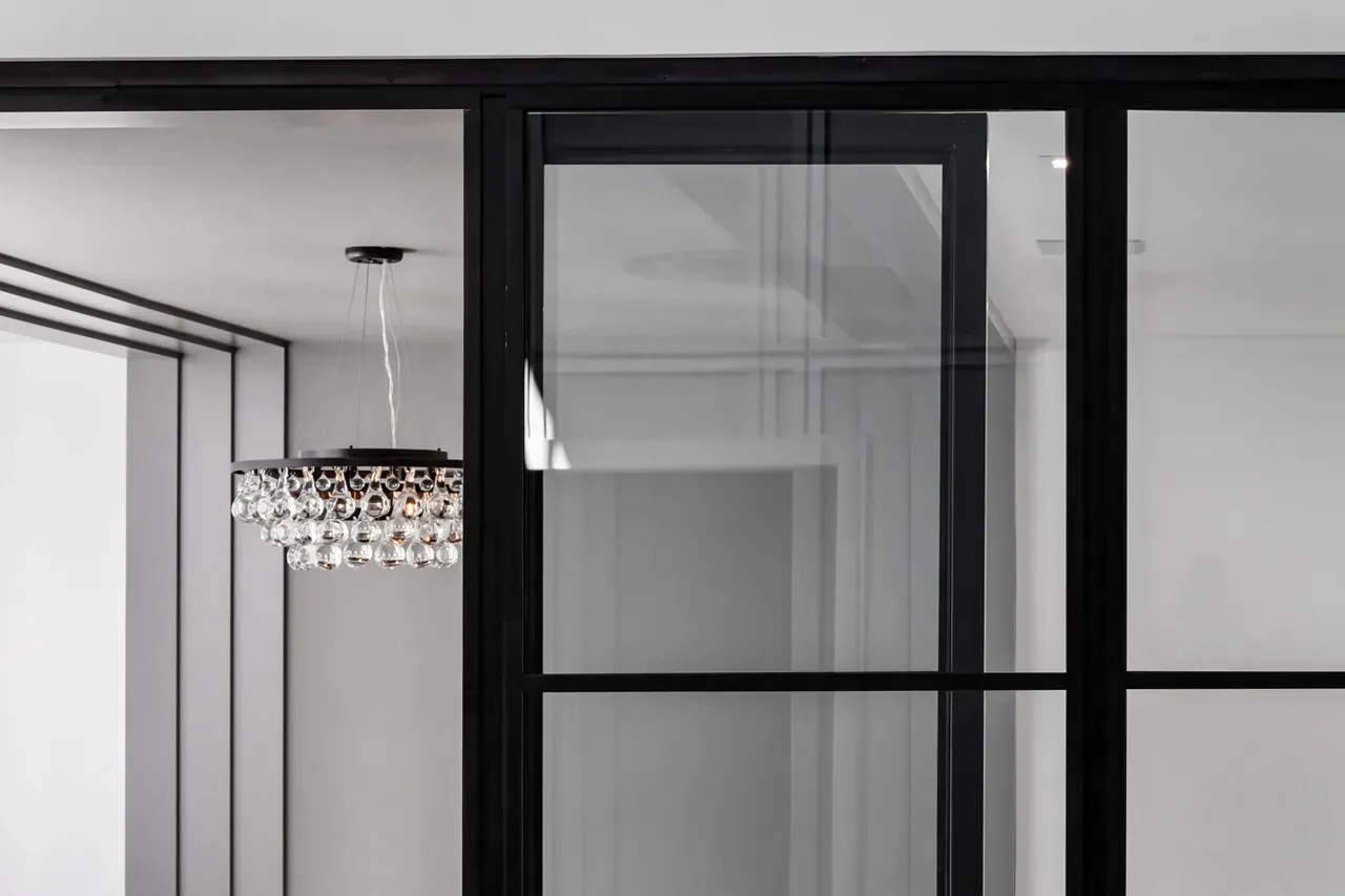 A room with a sliding glass door and a chandelier hanging from the ceiling.