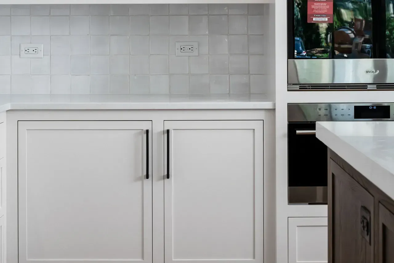 A kitchen with white cabinets and a stainless steel oven.