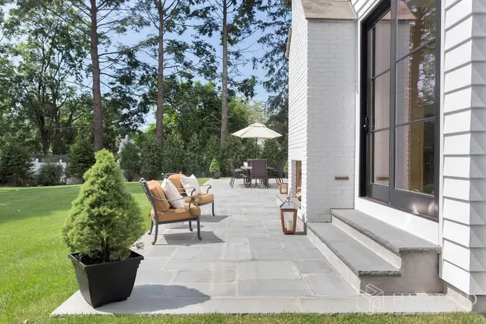 There is a patio with a fireplace and chairs in the backyard of a house.