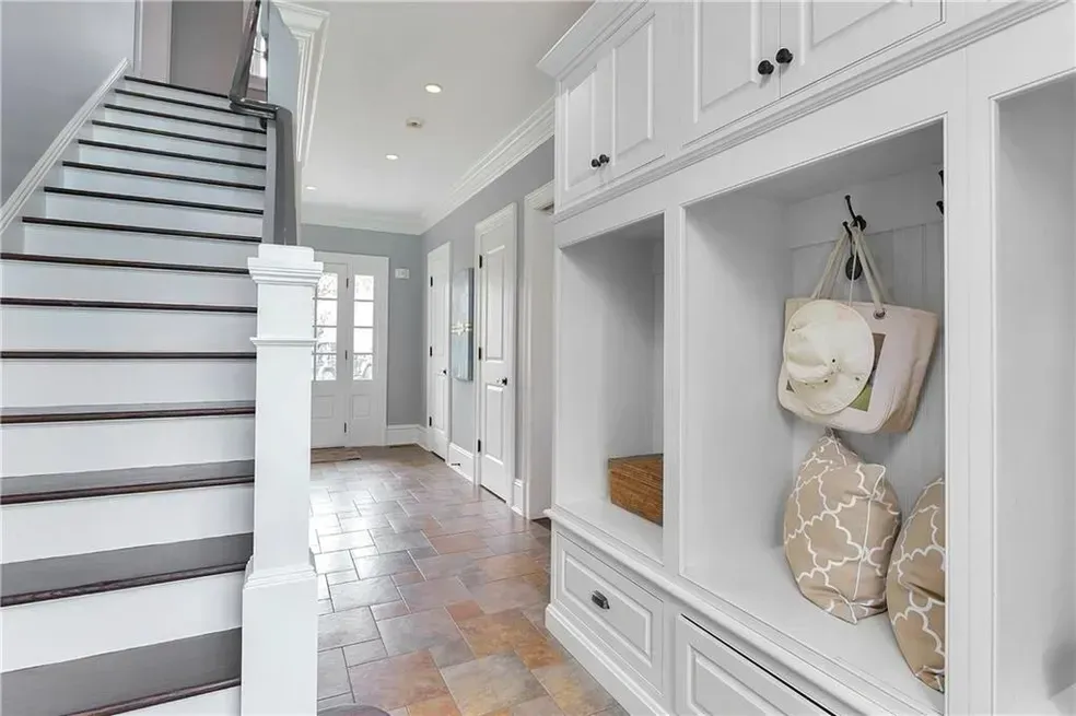 A hallway with white cabinets and stairs in a house.