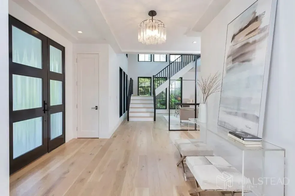 A hallway with hardwood floors and a staircase in the background