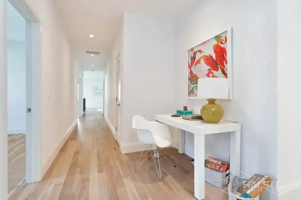 A hallway with a desk and chair in the middle of it.