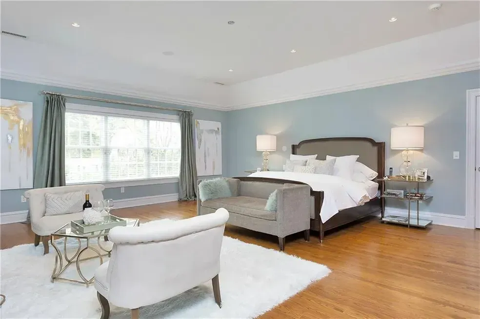 A bedroom with a large bed , chairs , a table and a rug.