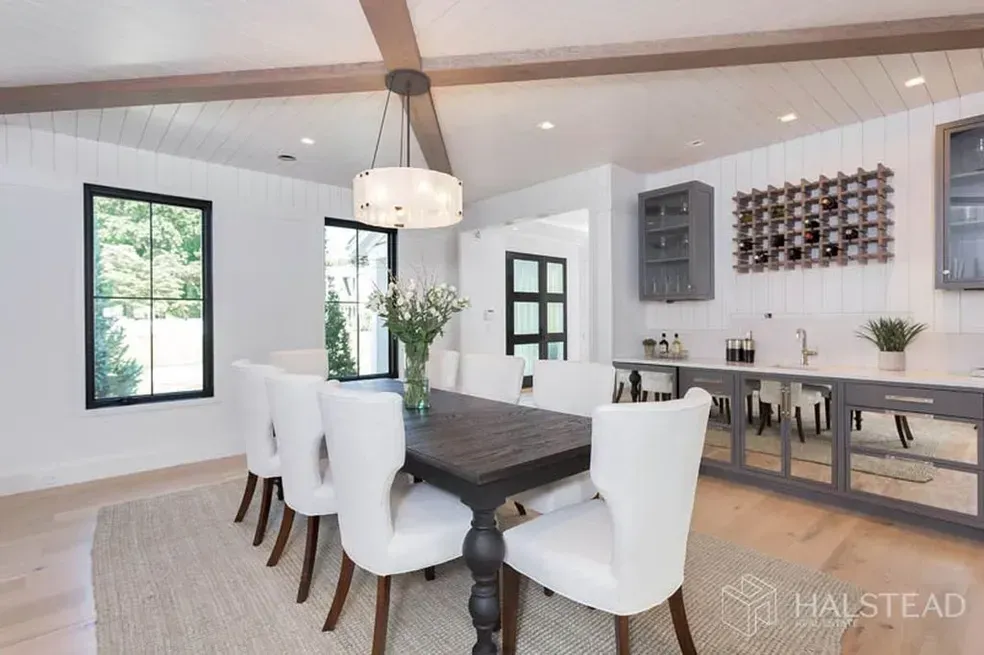 A dining room with a table and chairs and a wine rack on the wall.
