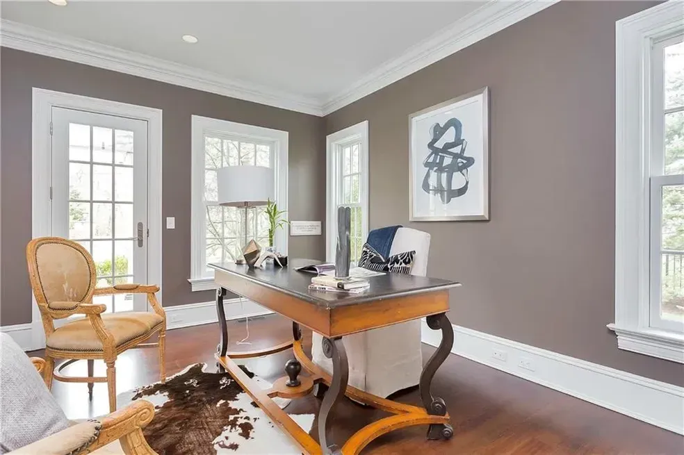 A home office with a desk , chair , and painting on the wall.