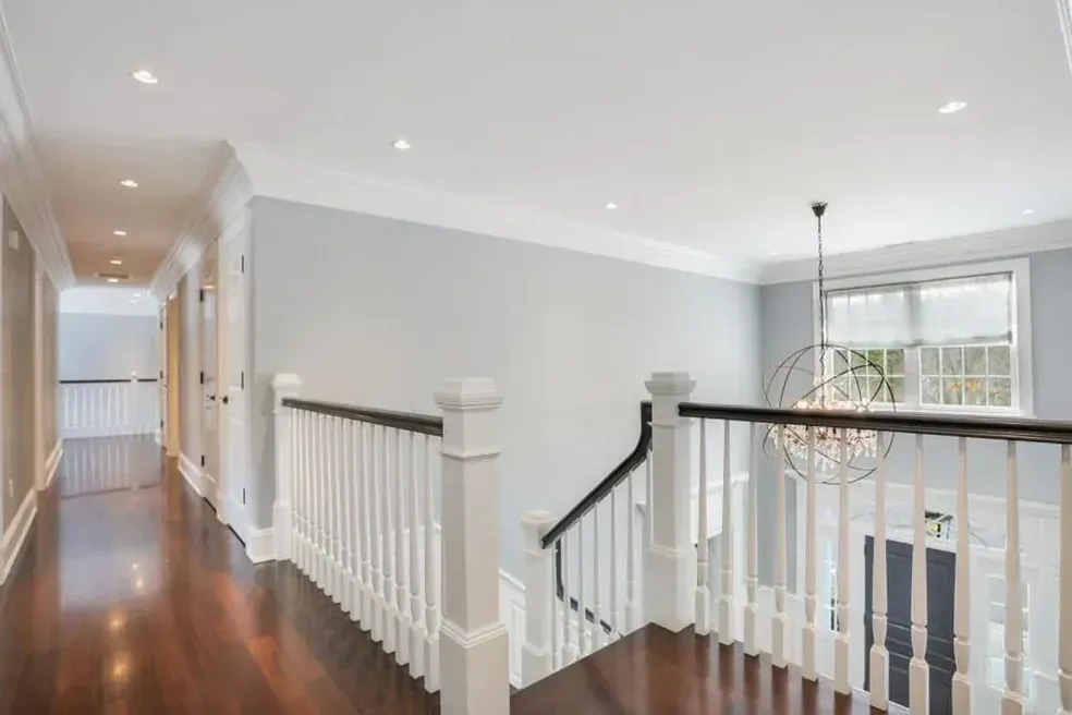 A hallway with a staircase and a chandelier in a house.