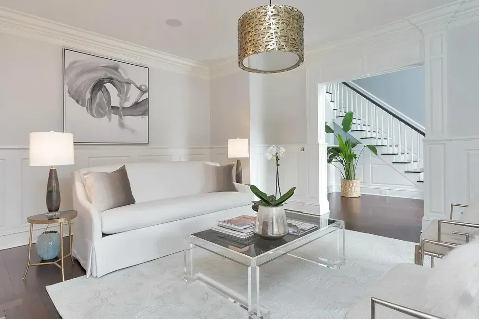 A living room with a white couch and a clear coffee table.