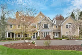 A large house with a lot of windows is sitting on top of a lush green hillside.