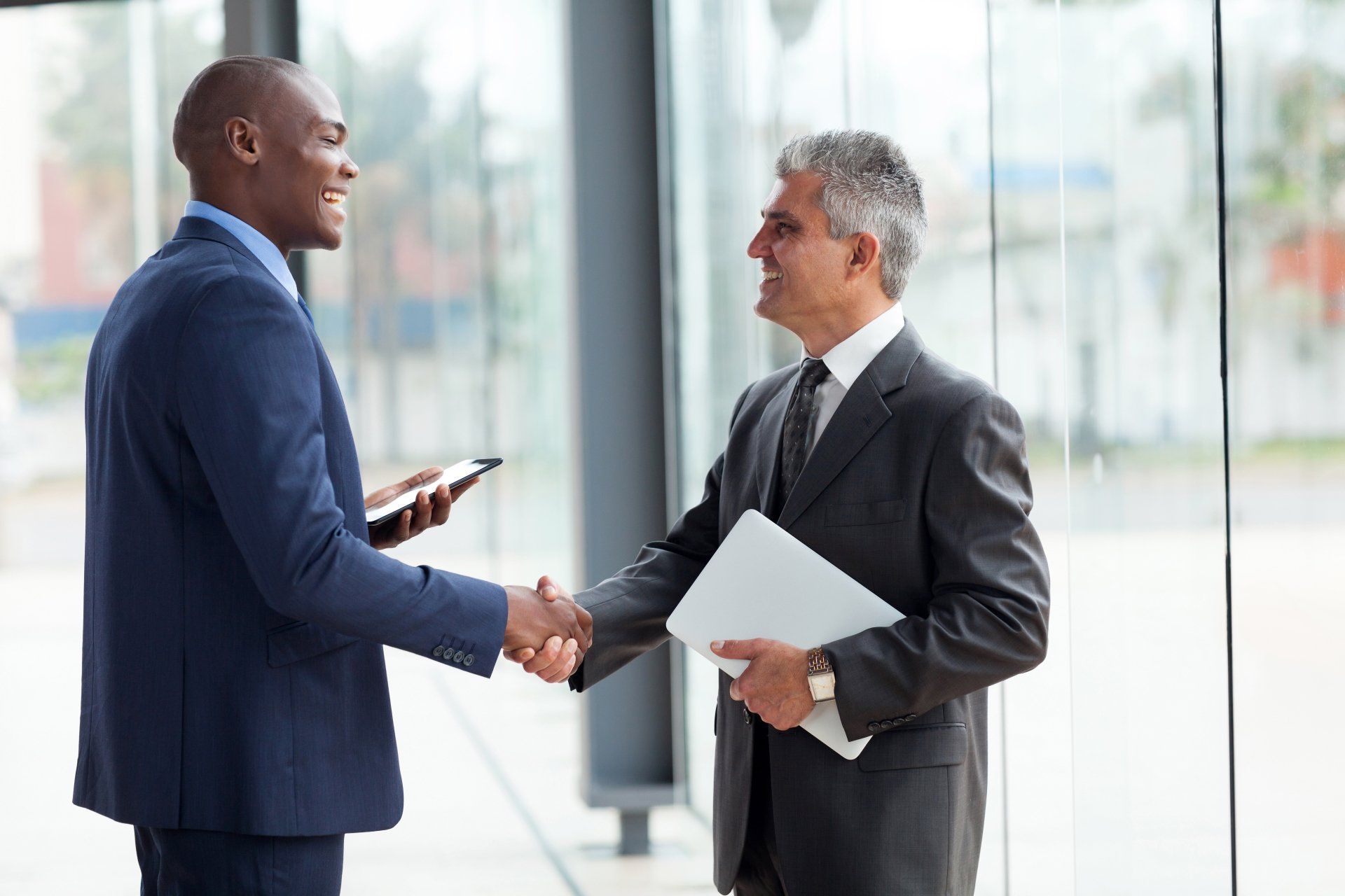 two cheerful businessman handshaking in conference hall