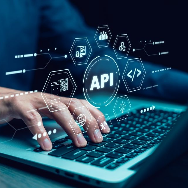 Person typing on a laptop with an API graphic overlay in a dim setting.