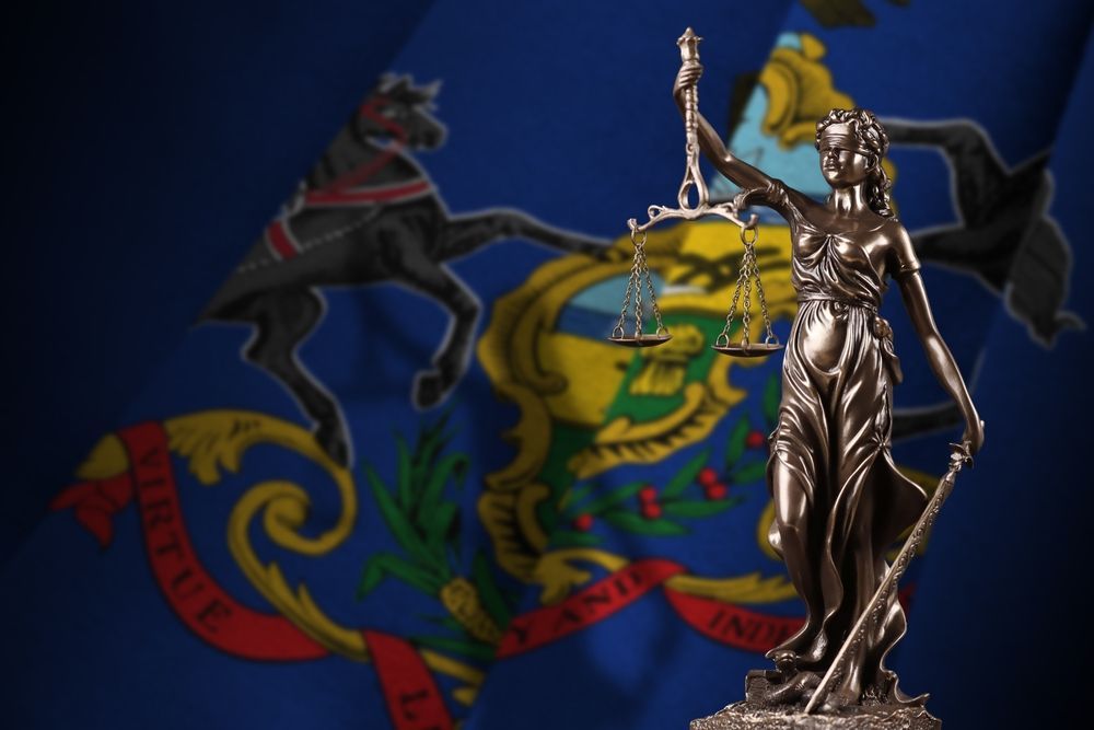 A statue of lady justice in front of a pennsylvania flag