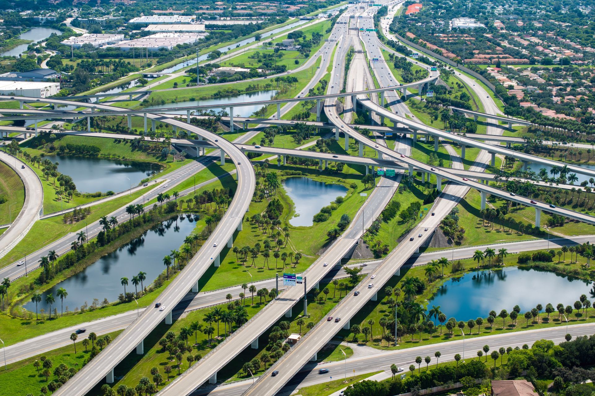 An aerial view of a highway intersection surrounded by trees and water.