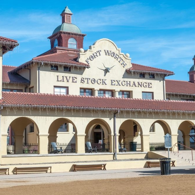 The Fort Worth Live Stock Exchange building, a historic cream-colored structure with arched entryways and a clock tower.