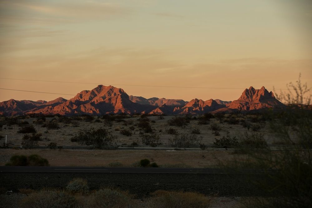 Golden sunset over rugged mountains in a desert landscape.
