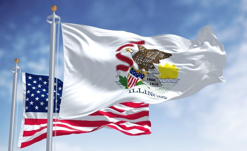 Illinois state flag and American flag waving in the wind against a blue sky with some clouds.