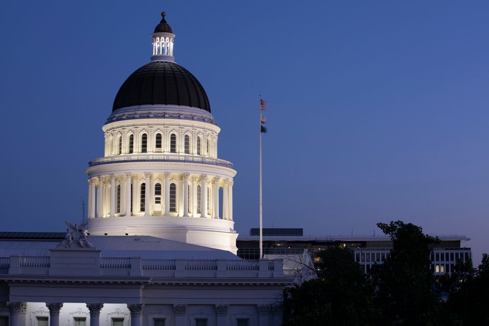 California State Capitol building dome at dusk, lit against a blue sky.