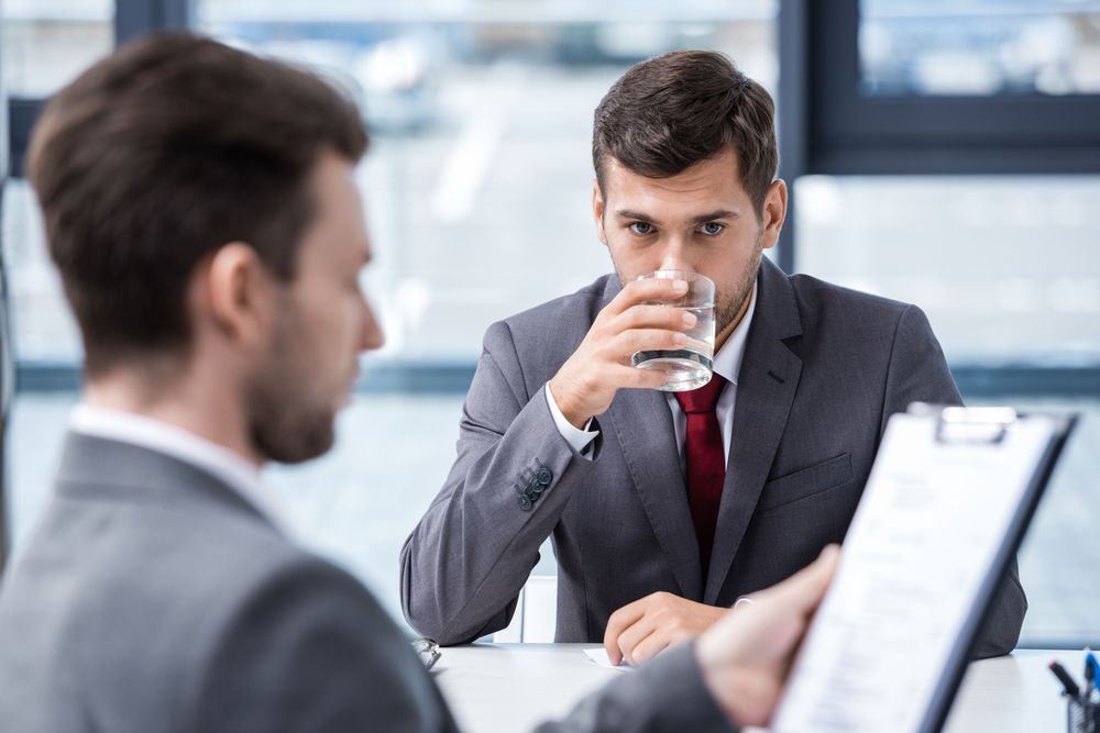 Man drinking a glass of water at a job interview

