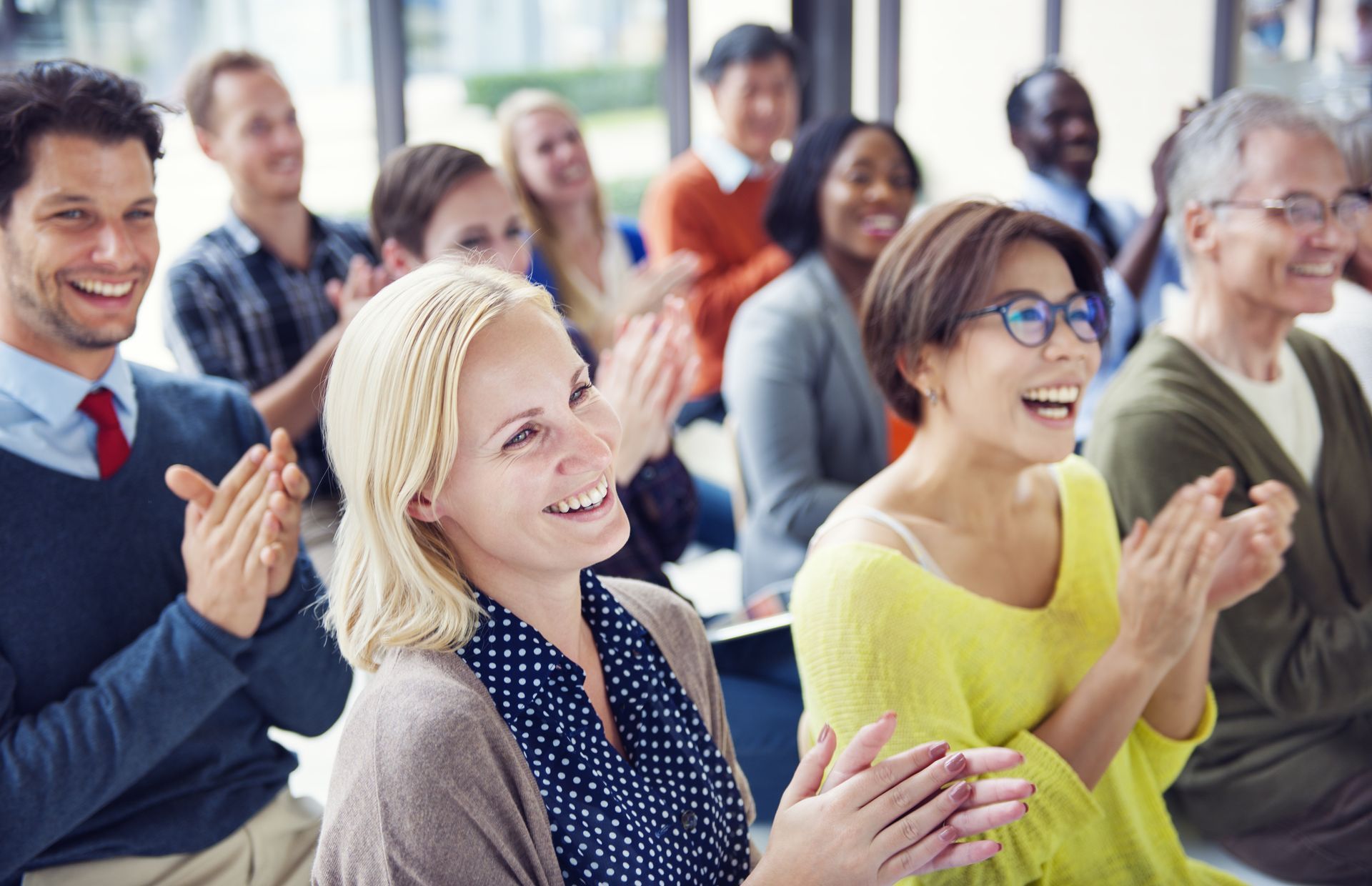 A group of safety sensitive people are sitting in a room clapping their hands.