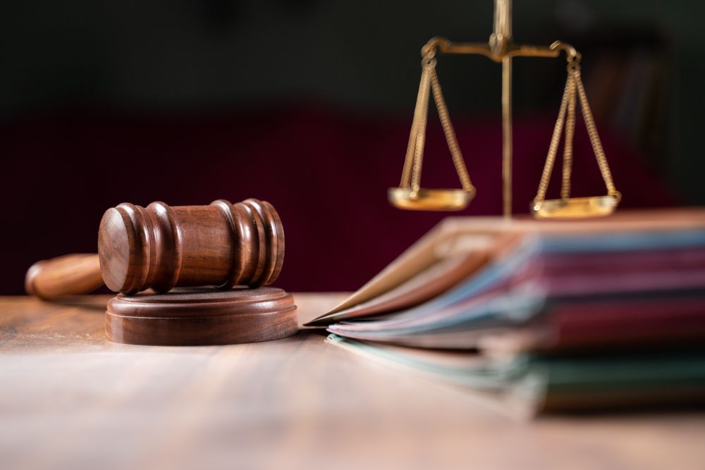 A wooden judge 's gavel and scales of justice are on a wooden table.