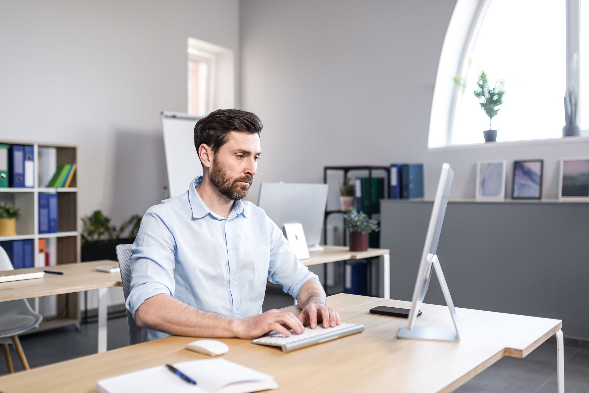 A man is sitting at a desk in front of a computer researching  a  fake degree certificate