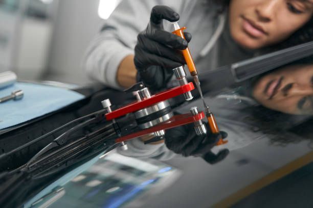 Technician repairing a windshield chip with tools.