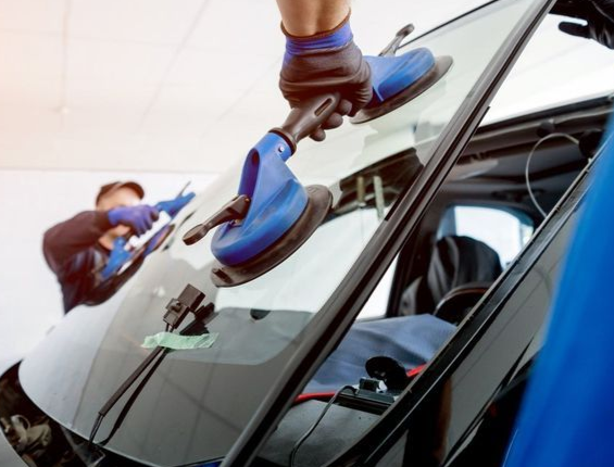 Two mechanics installing a new car windshield.
