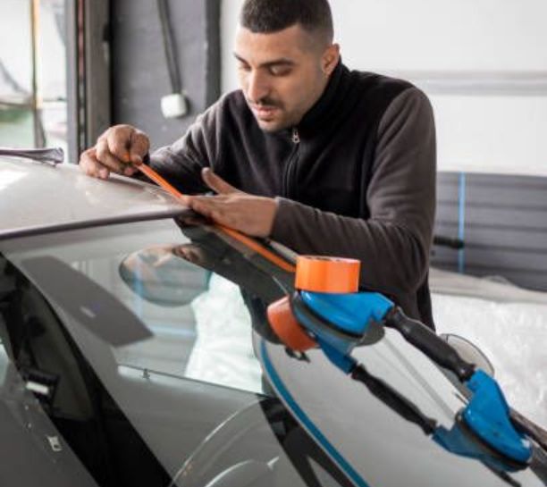 Technician applying protective tape to a car roof.