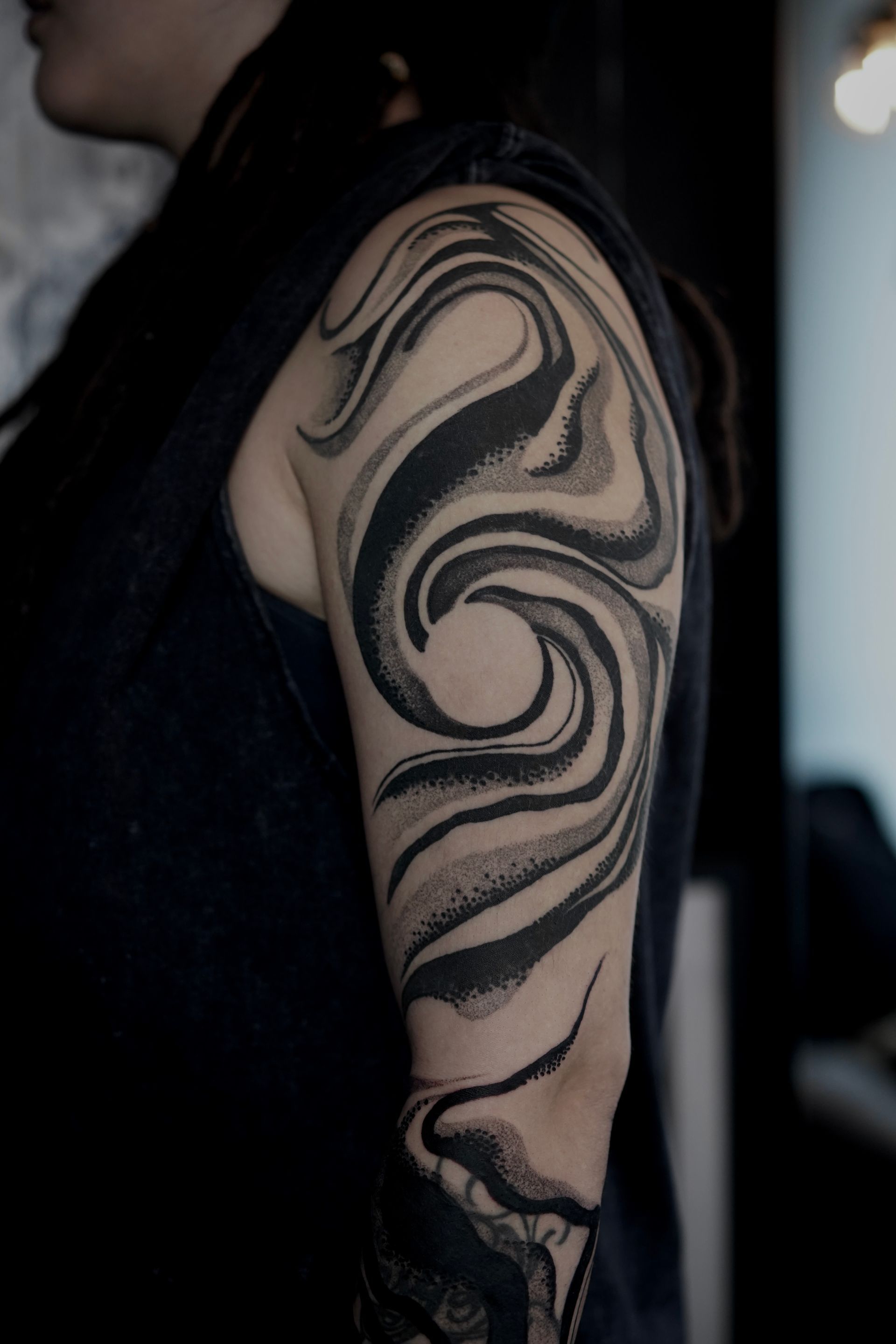Woman with a black swirl tattoo covering most of her arm.
