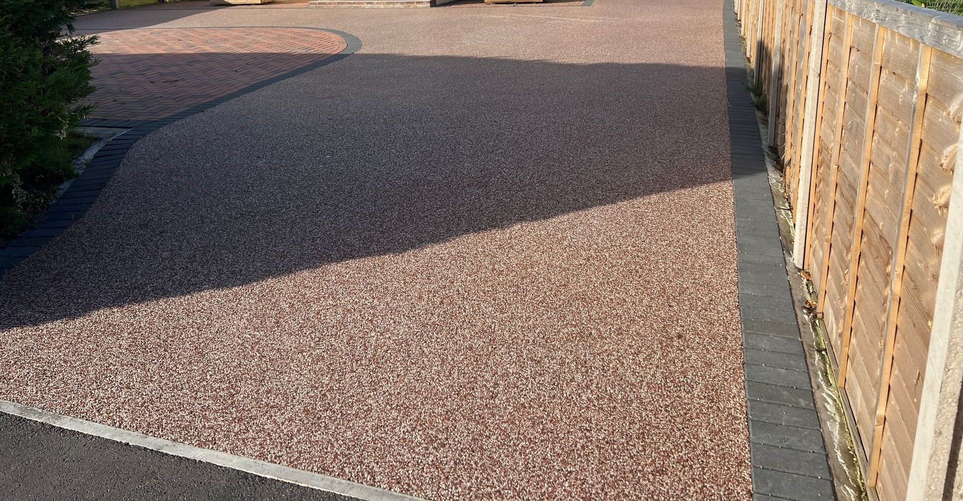 Gravel driveway with a wooden fence on the right side. The driveway appears to be light brown.