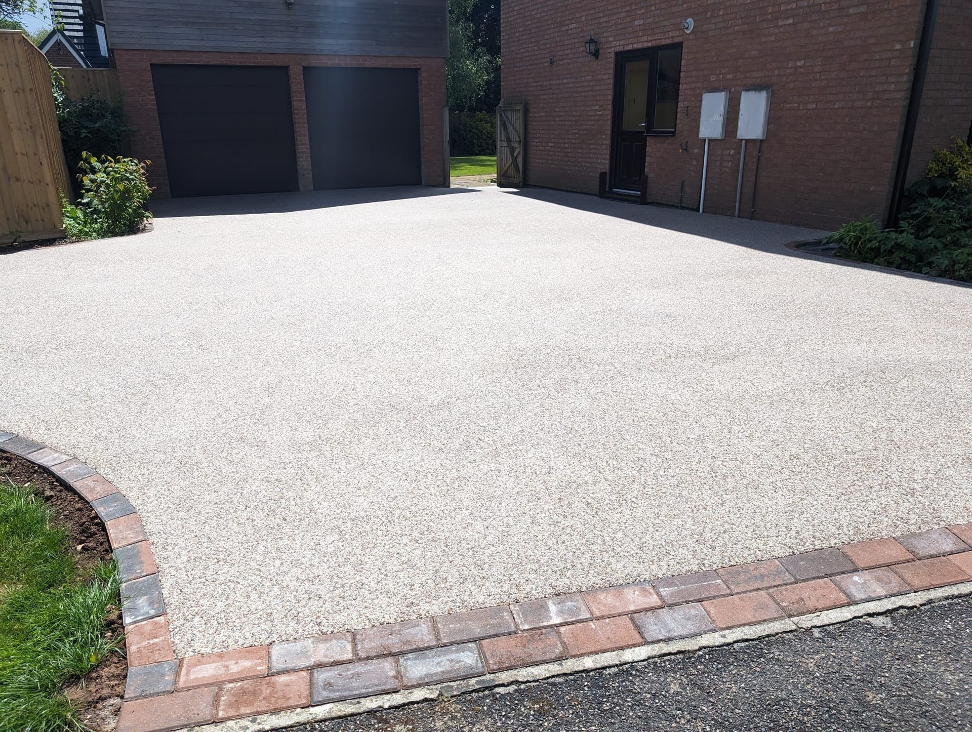 White resin driveway with a red block edging, as the entrance for a red block house.