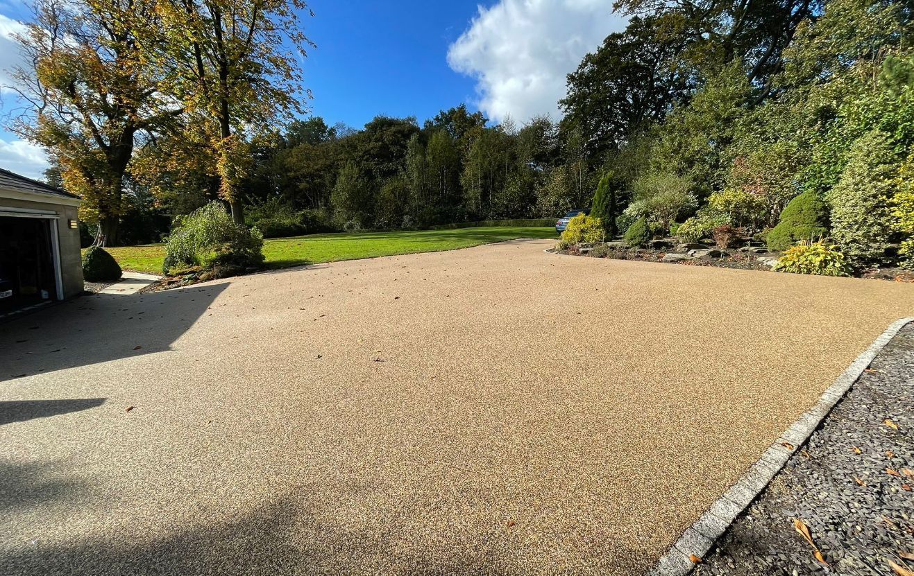 A gravel driveway leading to a garage with trees in the background.