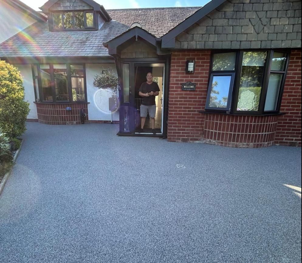 A man is standing in front of a brick house