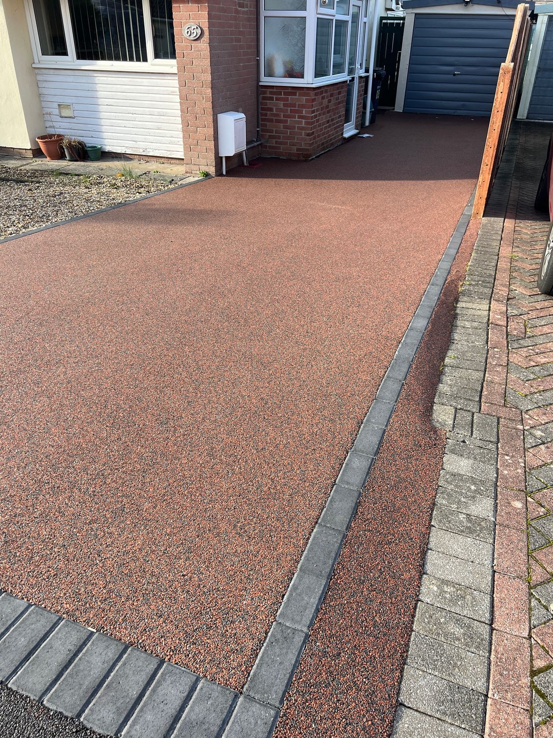 A driveway with bricks and gravel in front of a house.