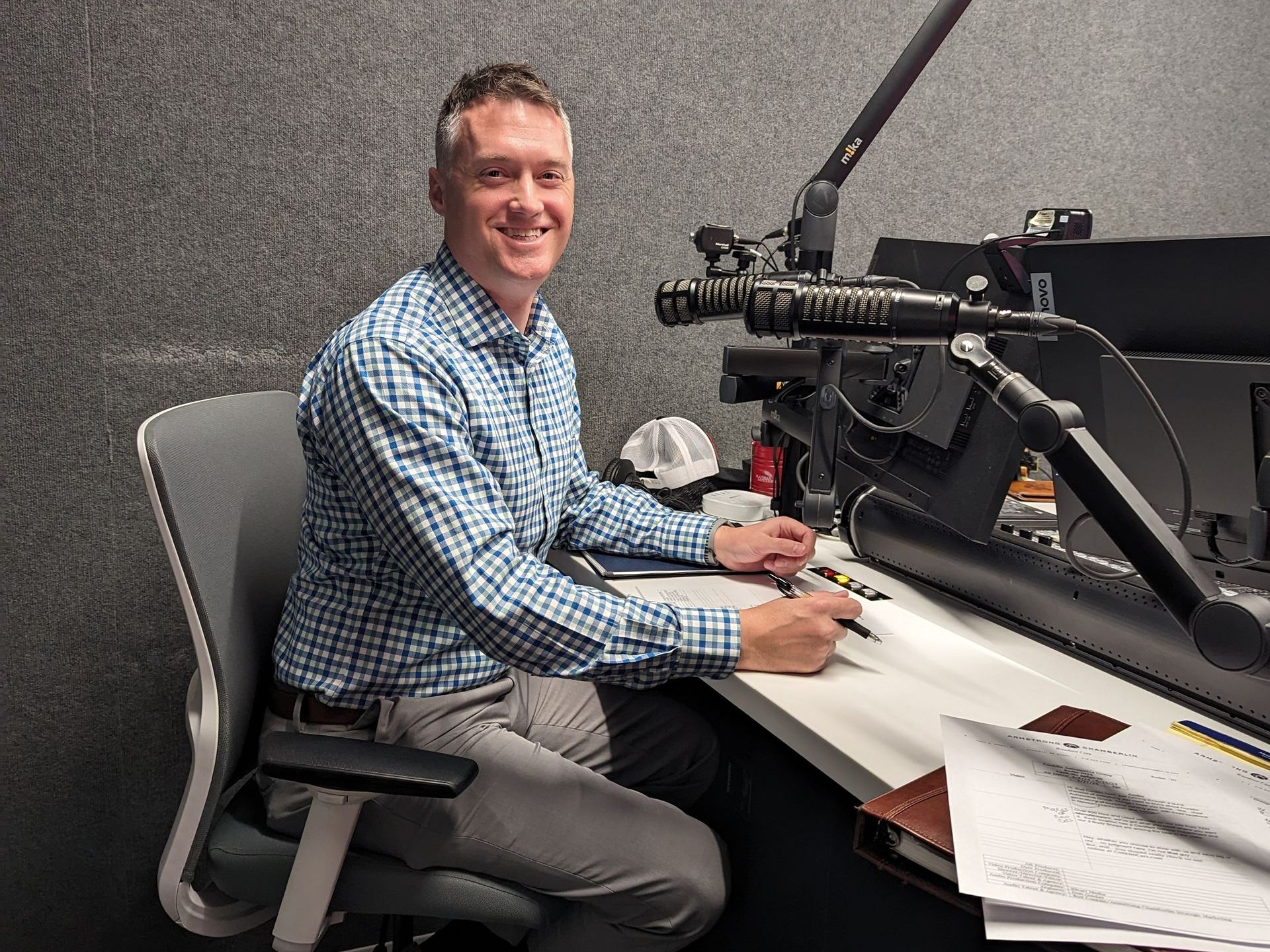 A man is sitting at a desk in front of a microphone.
