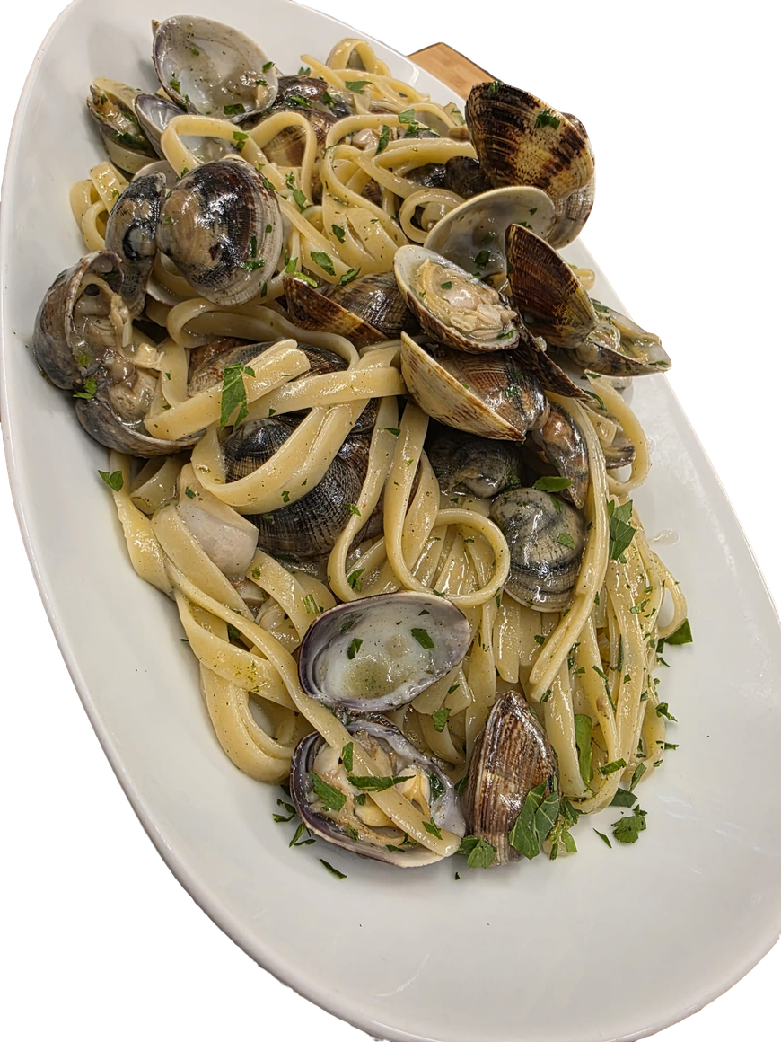 Pasta con vongole ed erbe aromatiche servita su un piatto ovale bianco.