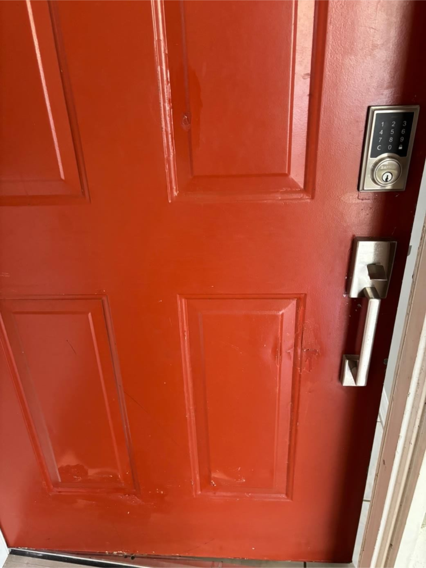 Red door with a silver door closer and latch at the top.