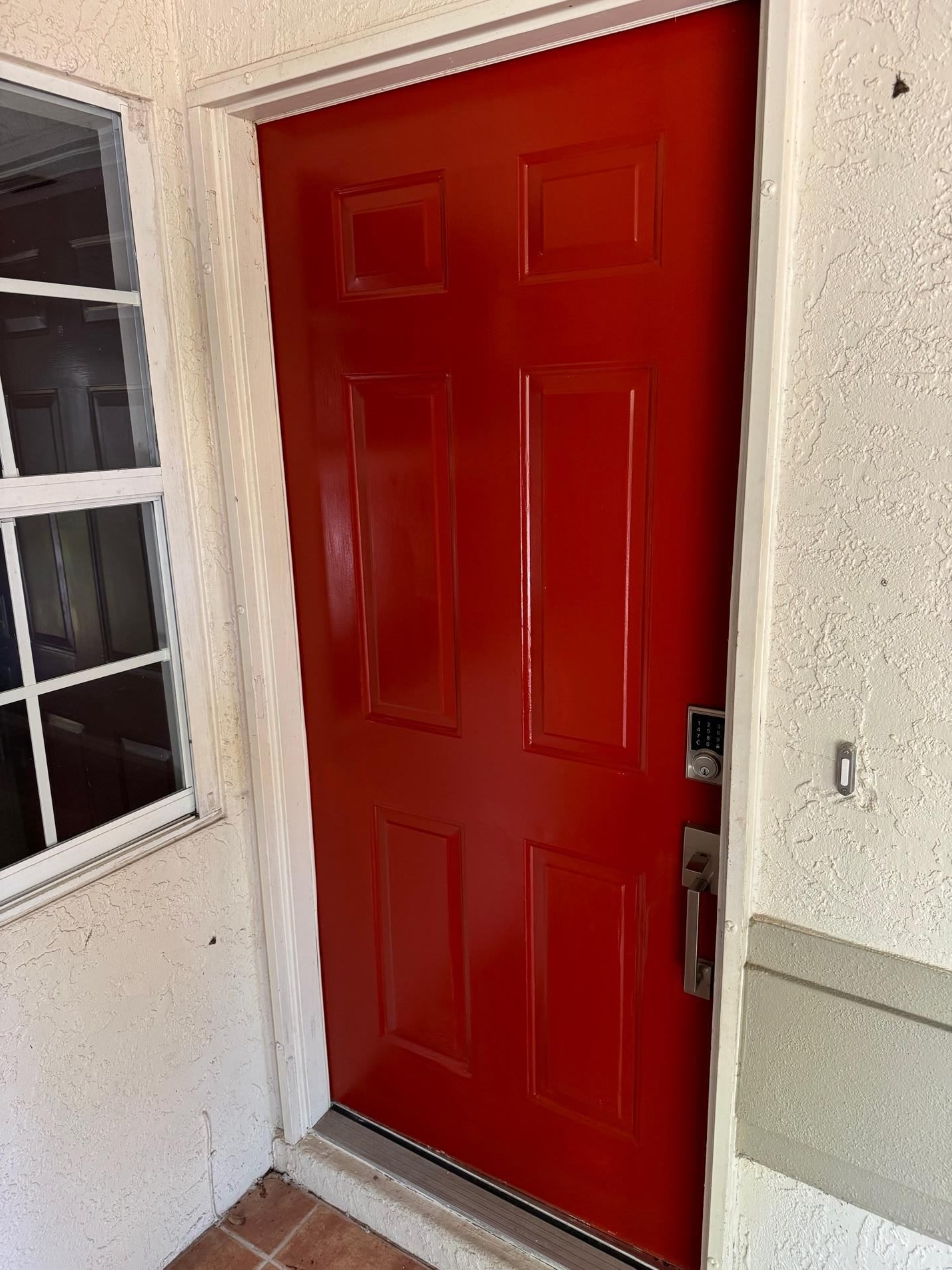 Red front door panel beneath a white ceiling, viewed from below with a window frame at the bottom.